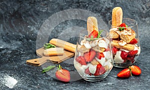 Tiramisu. Homemade tiramisu cake with fresh strawberry, mascarpone and mint in glass . Tiramisu portion on plate on dark