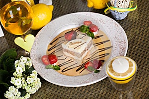 Tiramisu on a plate with strawberries and sauce in still life, chocolate design