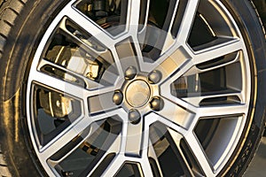 Tire and alloy wheel of a modern car on the ground, car exterior details.