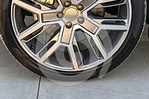 Tire and alloy wheel of a modern car on the ground, car exterior details