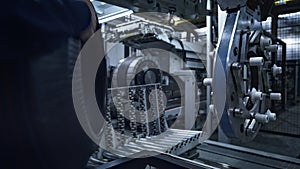 Tire factory employee working with modern industrial machine taking production