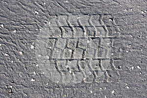 Tire imprints on old cracked asphalt road