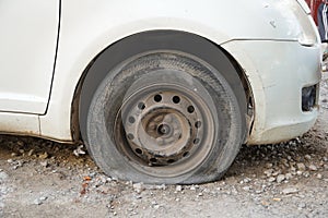 Tire leak, close up wheel of old white vintage car. Car wheel flat tire on the road. Deflated the tyre of an old car next to a