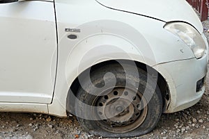 Tire leak, close up wheel of old white vintage car. Car wheel flat tire on the road. Deflated the tyre of an old car next to a