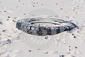 Tire left on a beach, environment pollution concept