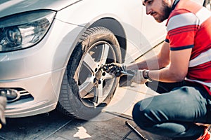 Tire maintenance, damaged car tyre or changing seasonal tires using wrench. Changing a flat car tire on the sideroad or in the cou