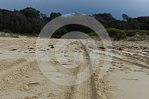 Tire marks in soft sand uphill on a beach