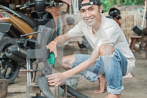 Tire repairman smiles at the camera while pouring fuel on a traditional press while patching tires