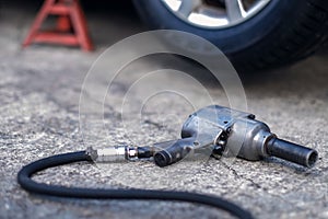 Tire Replacement concept. Electric Screwdriver Wrench for Wheel Nuts lay on the Floor in Garage