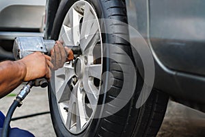 Tire Replacement concept. Mechanic Using Electric Screwdriver Wrench for Wheel Nuts in Garage. Car Maintenance