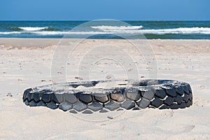 Tire on a sandy beach, environment pollution concept