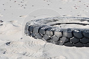 Tire on a sandy beach, environment pollution concept