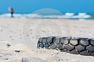 Tire on a sandy beach, environment pollution concept