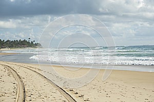 tire tracks and footprints in the sand in front of the beach