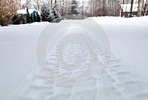 Tire tracks in freshly fallen snow in a residential neighborhood