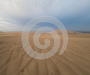 Tire tracks over the sand at Ica desert, dunes in the horizon