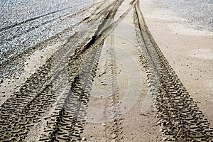 Tire tracks in the sand in perspective on the sea beach