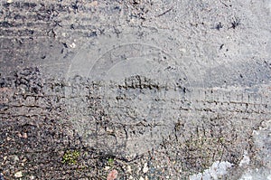 Tire tracks on the sand. Wheel tracks on dirt. Dark tire tracks background with snow and water. Wheel track on muddy