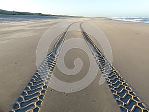 Tire tracks on smooth sandy deserted beach