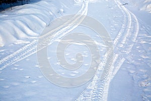 Tire tracks on a snowy road. Winter road not cleared of snow. Hard to drive. Village country road
