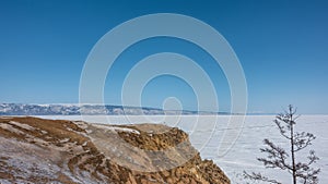 Tire tracks are visible on a frozen lake covered with snow.