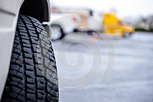 Tire tread of semi truck wheel on the background of another semi truck standing on the parking lot