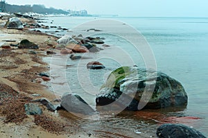 The tire in the water between the stones, car tire pollutes the sea