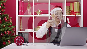 Tired 40s corporate employee in Santa hat participates in Online Christmas party