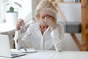 Tired 60 years old businesswoman taking off glasses.