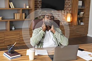 Tired adult black businessman in glasses suffering from neck pain, discomfort long hours of sedentary