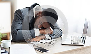 Tired african american businessman having a nap at workplace