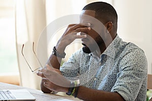 Tired african american businessman holding glasses feeling eye strain