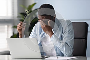 Tired african American male employee suffer from headache