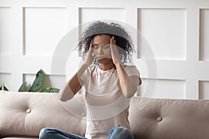 Tired black woman massaging temples suffering from migraine photo