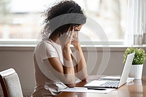 Unwell biracial woman suffer from headache working at laptop photo