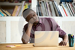 Tired African American office worker suffering from neck pain