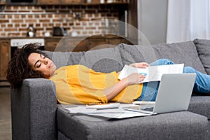 tired african american woman sleeping on couch after work