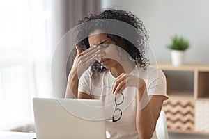 Tired African American woman taking off glasses, feeling eye strain photo