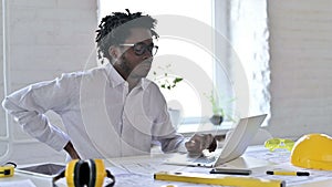Tired African architecture engineer having back pain in office