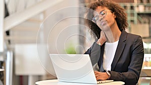 Tired African Businesswoman with Laptop having Neck Pain at Cafe