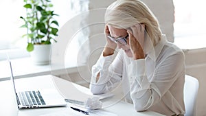 Tired aged businesswoman feel fatigue suffering from headache