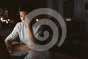 Tired Asian businessman working at his desk late at night