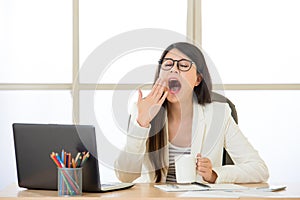Tired Asian businesswomen yawing at desk photo