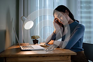 A tired Asian female college student is falling asleep at a table in her room in the evening