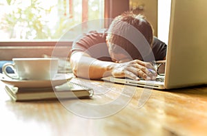 Tired asian man with head down on computer laptop while working.