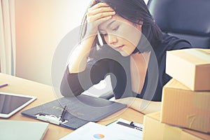 Tired Asian office worker with hand on her head headache