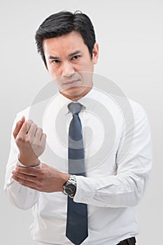 A tired Asian office worker is massaging his wrist from a wrist pain and showing the pain expression on his face, Fatigue and work