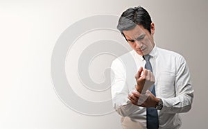 A tired Asian office worker is massaging his wrist from a wrist pain and showing the pain expression on his face with wide copy