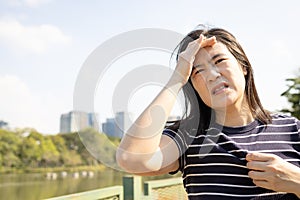 Tired asian woman with headache,dizziness,walking outdoor on sunny day,strong sunlight,hot weather,high temperature heat wave,