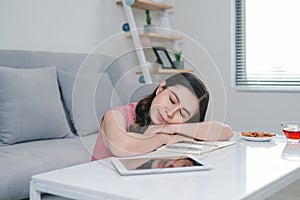 Tired asian woman sleeping near couch after work at home